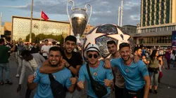 Fans of Manchester City pose in front of a giant replica of the Champions League trophy in Taksim Square ahead of the 2022-2023 UEFA Champions League final