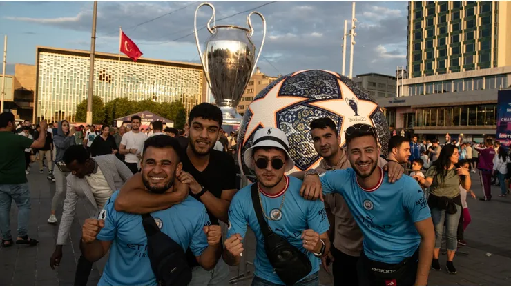 Fans of Manchester City pose in front of a giant replica of the Champions League trophy in Taksim Square ahead of the 2022-2023 UEFA Champions League final