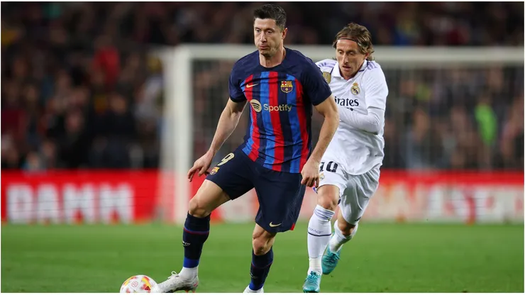 Robert Lewandowski of FC Barcelona runs with the ball whilst under pressure from Luka Modric of Real Madrid