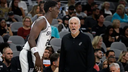 Gregg Popovich head coach of the San Antonio Spurs confers with Charles Bediako