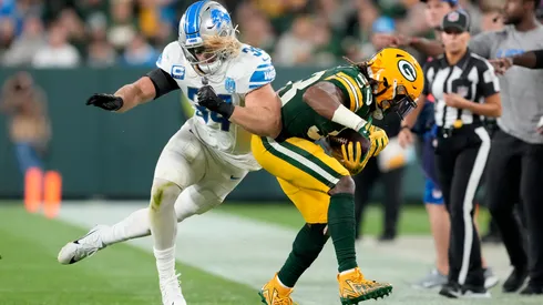Alex Anzalone #34 of the Detroit Lions pushes Aaron Jones #33 of the Green Bay Packers out of bounds