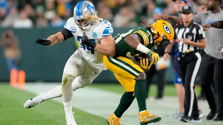 Alex Anzalone #34 of the Detroit Lions pushes Aaron Jones #33 of the Green Bay Packers out of bounds