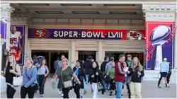 Visitors walk in front of an entrance to Caesars Palace with Super Bowl LVIII signage displayed