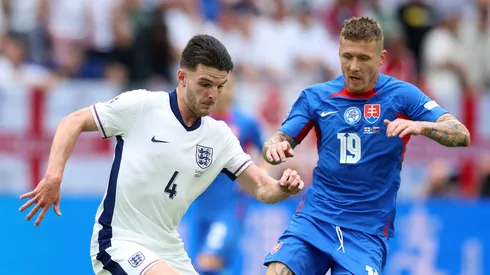 Declan Rice of England runs with the ball under pressure from Juraj Kucka of Slovakia during the UEFA EURO 2024 round of 16 match between England and Slovakia at Arena AufSchalke on June 30, 2024 in Gelsenkirchen, Germany.
