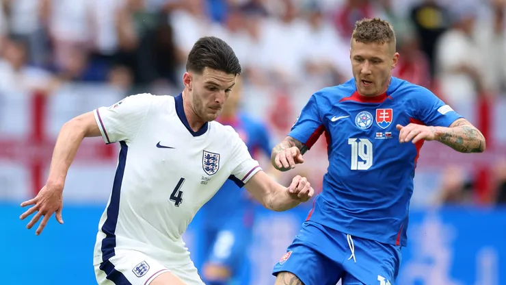 Declan Rice of England runs with the ball under pressure from Juraj Kucka of Slovakia during the UEFA EURO 2024 round of 16 match between England and Slovakia at Arena AufSchalke on June 30, 2024 in Gelsenkirchen, Germany.