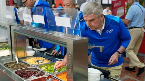 IOC President Thomas Bach tries food from a salad bar while touring the Olympic Village ahead of the start of the Paris 2024 Olympic Games on July 22, 2024 in Paris, France.
