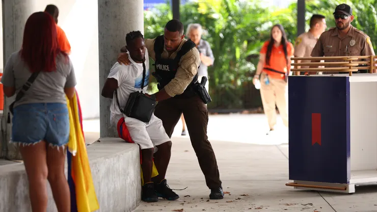 A fan of Colombia is detained by a police officer outside the stadium prior the CONMEBOL Copa America 2024 Final match between Argentina and Colombia at Hard Rock Stadium