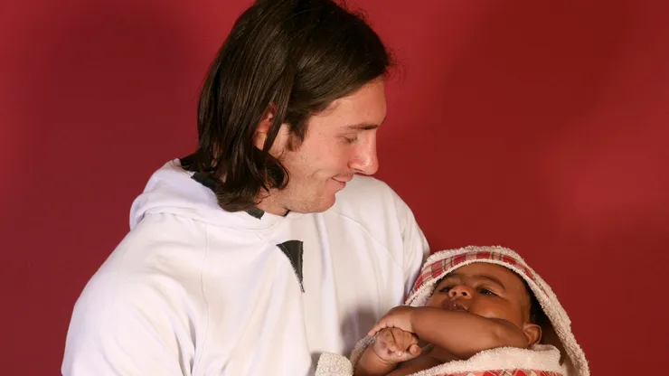 A young Lionel Messi holding a baby Lamine Yamal.