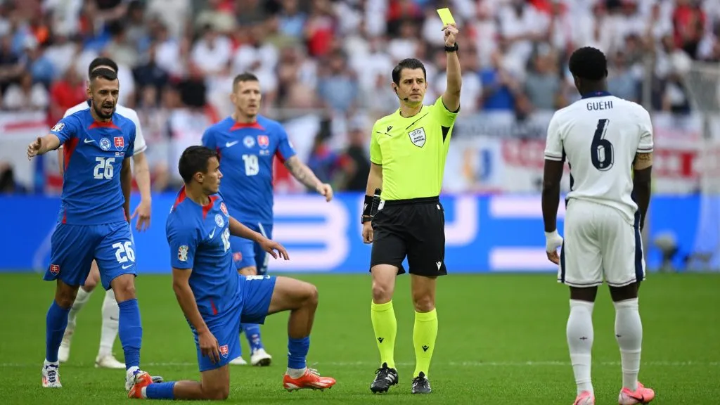 Referee Umut Meler shows a yellow card to Marc Guehi of England after he fouls David Strelec of Slovakia. Photo by Clive Mason/Getty Images.