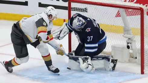 Connor Hellebuyck #37 of the Winnipeg Jets makes a save on Brett Howden #21 of the Vegas Golden Knights