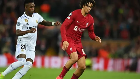 Trent Alexander-Arnold of Liverpool runs with the ball whilst under pressure from Vinicius Junior of Real Madrid