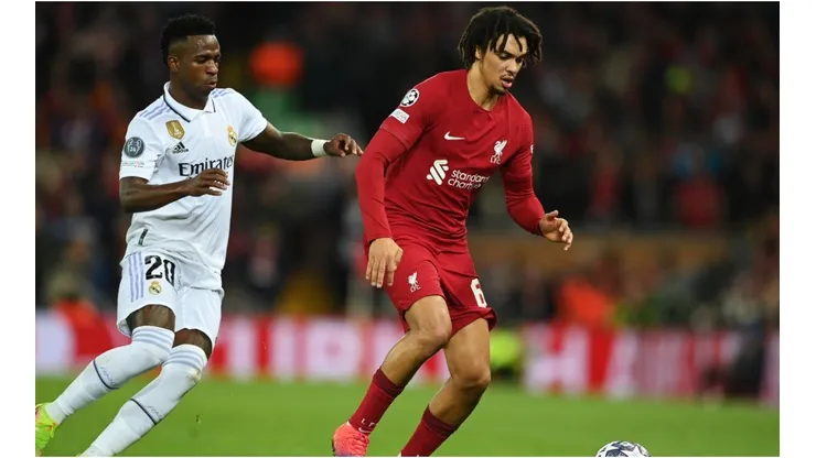 Trent Alexander-Arnold of Liverpool runs with the ball whilst under pressure from Vinicius Junior of Real Madrid