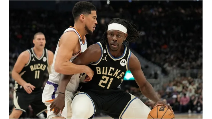 Jrue Holiday #21 of the Milwaukee Bucks dribbles the ball against Devin Booker #1 of the Phoenix Suns