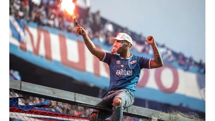 A fan with a flare wears a mask of Luis Suarez during the unveiling of the Uruguayan player Luis Suarez as the new player of Nacional at the Parque Central Stadium on July 31, 2022 in Montevideo, Uruguay.