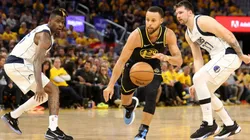 Stephen Curry #30 of the Golden State Warriors drives past Reggie Bullock #25 and Luka Doncic #77 of the Dallas Mavericks