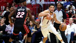 Devin Booker of the Phoenix Suns drives against Jimmy Butler of the Miami Heat