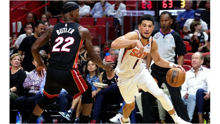 Devin Booker of the Phoenix Suns drives against Jimmy Butler of the Miami Heat