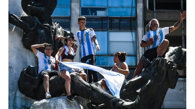Fans of Argentina climb a monument to celebrate as they gather for the victory parade of the Argentina men's national football team after winning the FIFA World Cup Qatar 2022 on December 20, 2022 in Buenos Aires, Argentina.