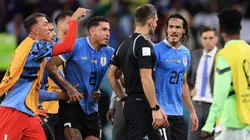 Uruguay players argue with referee Daniel Siebert.