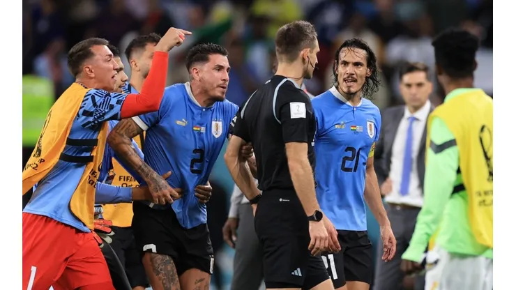 Uruguay players argue with referee Daniel Siebert.