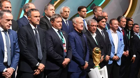 Managers of the national teams at Qatar 2022 pose with the FIFA World Cup trophy.