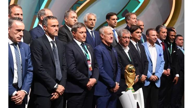 Managers of the national teams at Qatar 2022 pose with the FIFA World Cup trophy.