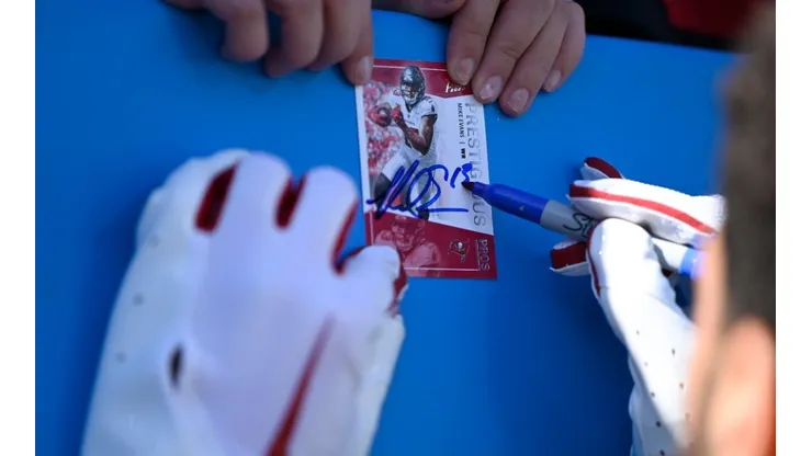 Mike Evans #13 of the Tampa Bay Buccaneers signs a card for a fan during pregame against the Carolina Panthers at Bank of America Stadium on October 23, 2022 in Charlotte, North Carolina.