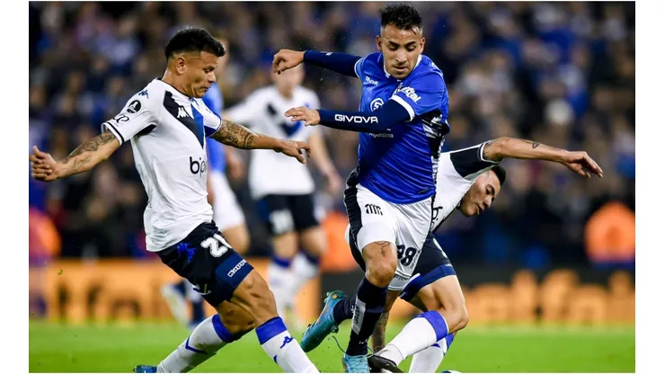 Matias Godoy of Talleres fights for the ball with Walter Bou (L) and Francisco Ortega (R) of Velez