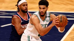 Jayson Tatum of the Boston Celtics looks to pass as Patty Mills of the Brooklyn Nets defends