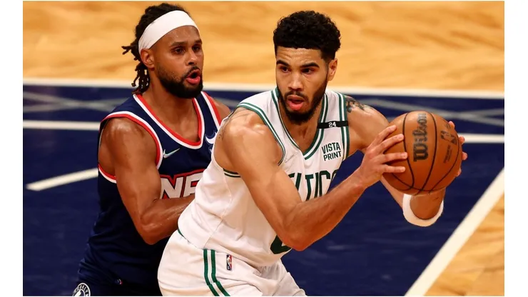 Jayson Tatum of the Boston Celtics looks to pass as Patty Mills of the Brooklyn Nets defends
