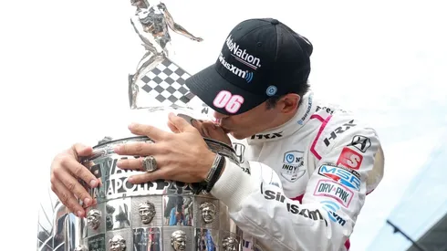 Helio Castroneves kisses the winner's trophy