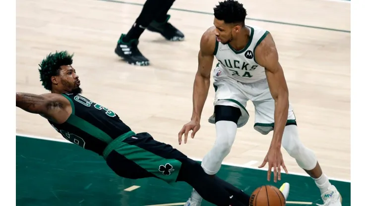 The Bucks Giannis Antetokounmpo (right) was called for a first quarter offensive foul as the Celtics Marcus Smart (left) hits the floor.