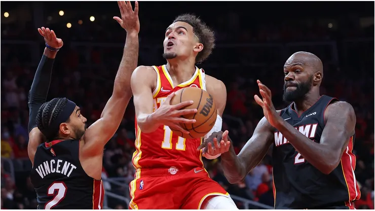 Trae Young of the Atlanta Hawks goes up for a layup against Gabe Vincent and Dewayne Dedmon of the Miami Heat