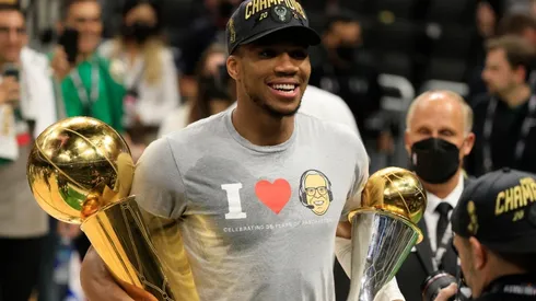 Giannis Antetokounmpo #34 of the Milwaukee Bucks holds the Bill Russell NBA Finals MVP Award and the Larry O'Brien Championship Trophy