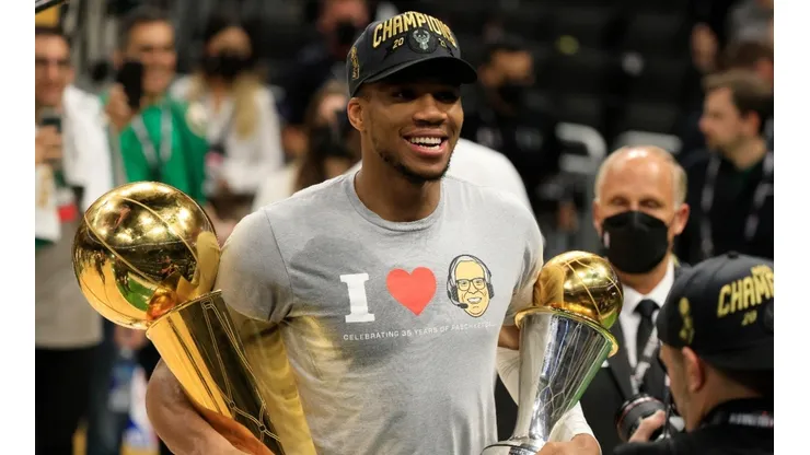 Giannis Antetokounmpo #34 of the Milwaukee Bucks holds the Bill Russell NBA Finals MVP Award and the Larry O'Brien Championship Trophy