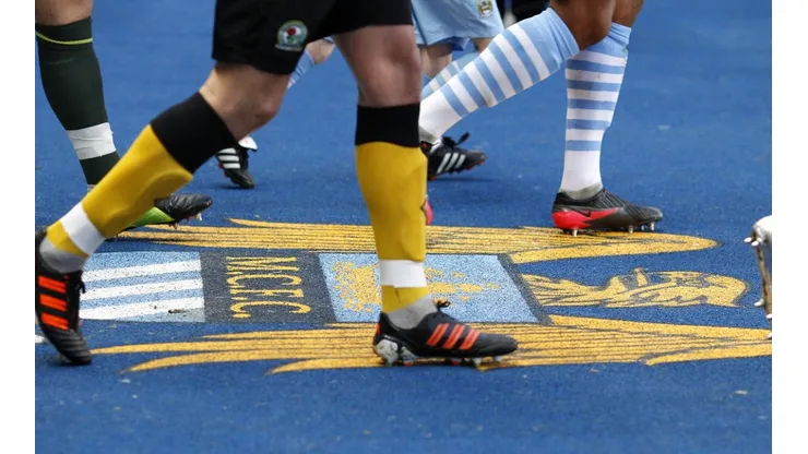 Players walk over the Manchester City's old crest