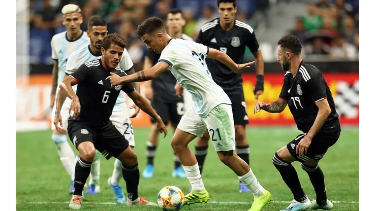 Paulo Dybala controls the ball surrounded by Mexican players in a friendly match