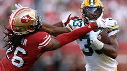 Aaron Jones #33 of the Green Bay Packers carries the ball fighting off the tackle of Josh Norman #26 of the San Francisco 49ers.