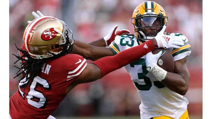 Aaron Jones #33 of the Green Bay Packers carries the ball fighting off the tackle of Josh Norman #26 of the San Francisco 49ers.