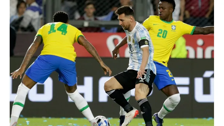 Lionel Messi of Argentina competes for the ball with Eder Militão (L) and Vinicius Junior (R) of Brazil