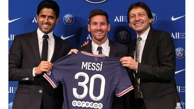 Lionel Messi poses with his jersey next to President Nasser Al Khelaifi and Leonardo