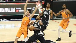 Paul George drives while Devin Booker tries to draw a charge. (Getty)