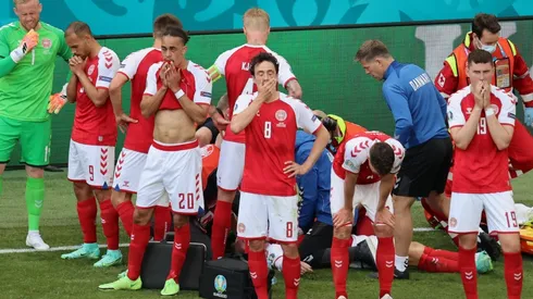 Denmark players look dejected whilst Christian Eriksen receives medical treatment. (Getty)