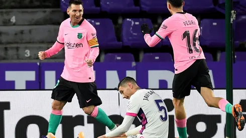 Lionel Messi (left) and Pedri (right) of Barcelona celebrate as Javier Sanchez of Real Valladolid (center) reacts.