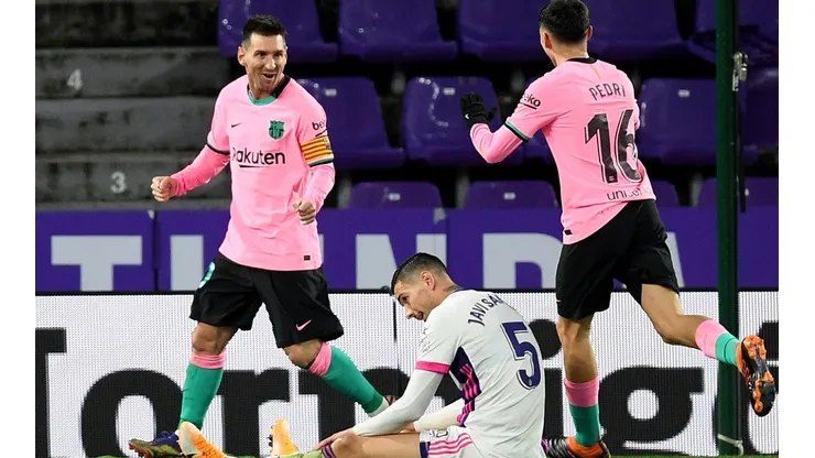 Lionel Messi (left) and Pedri (right) of Barcelona celebrate as Javier Sanchez of Real Valladolid (center) reacts.