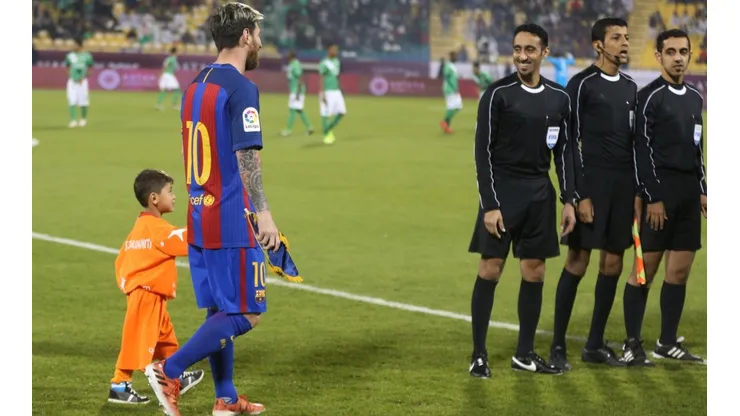 Afghan boy Murtaza Amadi walks with Lionel Messi of Barcelona in 2016. (Getty)