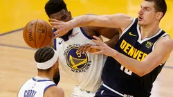 Nikola Jokic (Denver) passing the ball between Stephen Curry and Kevon Looney (Warriors). (Getty)