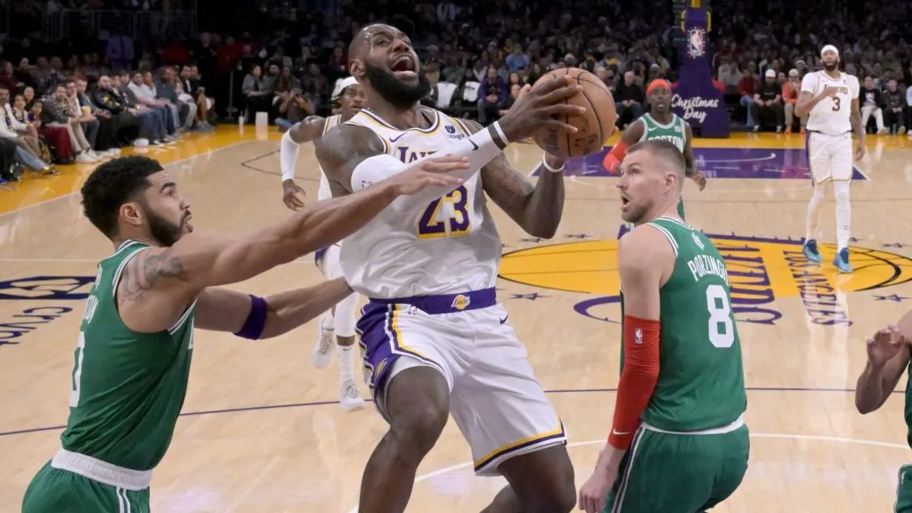 LeBron James #23 of the Los Angeles Lakers drives past Jayson Tatum #0 and Kristaps Porzingis #8 of the Boston Celtics in the first half at Crypto.com Arena on December 25, 2023 in Los Angeles, California.