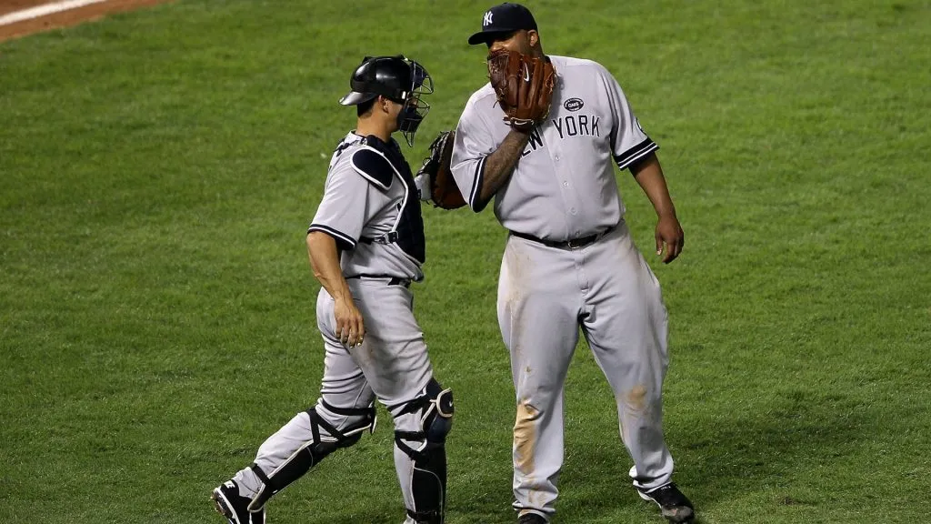 (L-R) Catcher Jorge Posada #20 and CC Sabathia #52 of the New York Yankees talk against the Texas Rangers in Game One of the ALCS during the 2010 MLB Playoffs at Rangers Ballpark in Arlington on October 15, 2010 in Arlington, Texas. (Photo by Elsa/Getty Images)