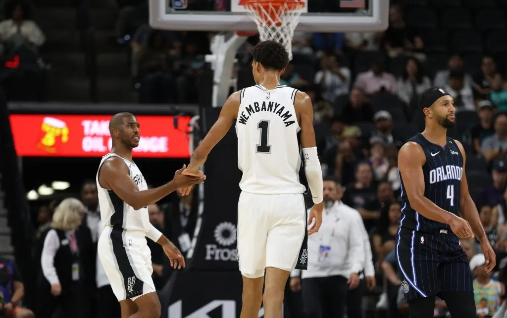 Victor Wembanyama #1 of the San Antonio Spurs slaps hands with Chris Paul #3 during action against the Orlando Magic in the first half of a preseason game at Frost Bank Center on October 9, 2024 in San Antonio, Texas.